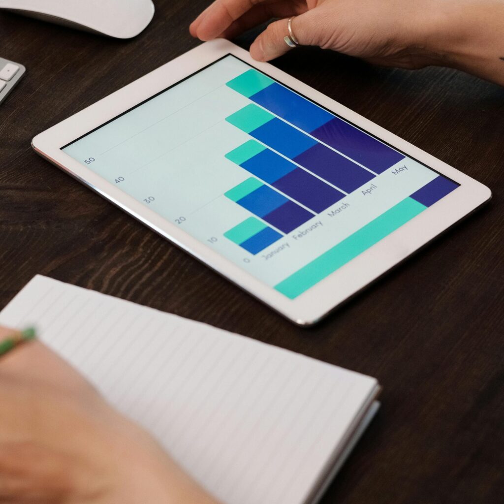 Home Focused person working on digital tablet analyzing business graphs at desk.